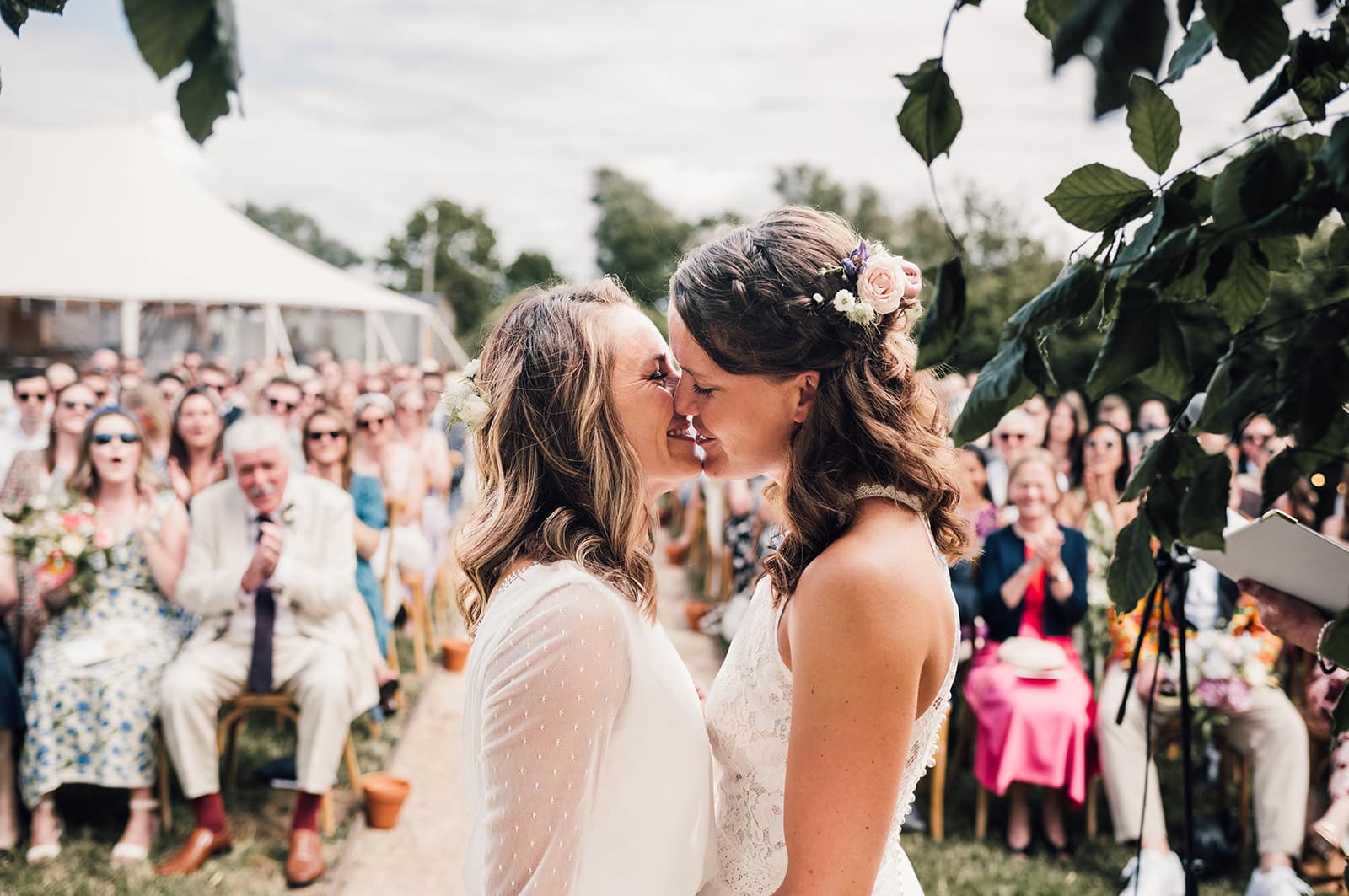 2 brides share a kiss at outdoor wedding at Willow Grange Farm near Cambridge