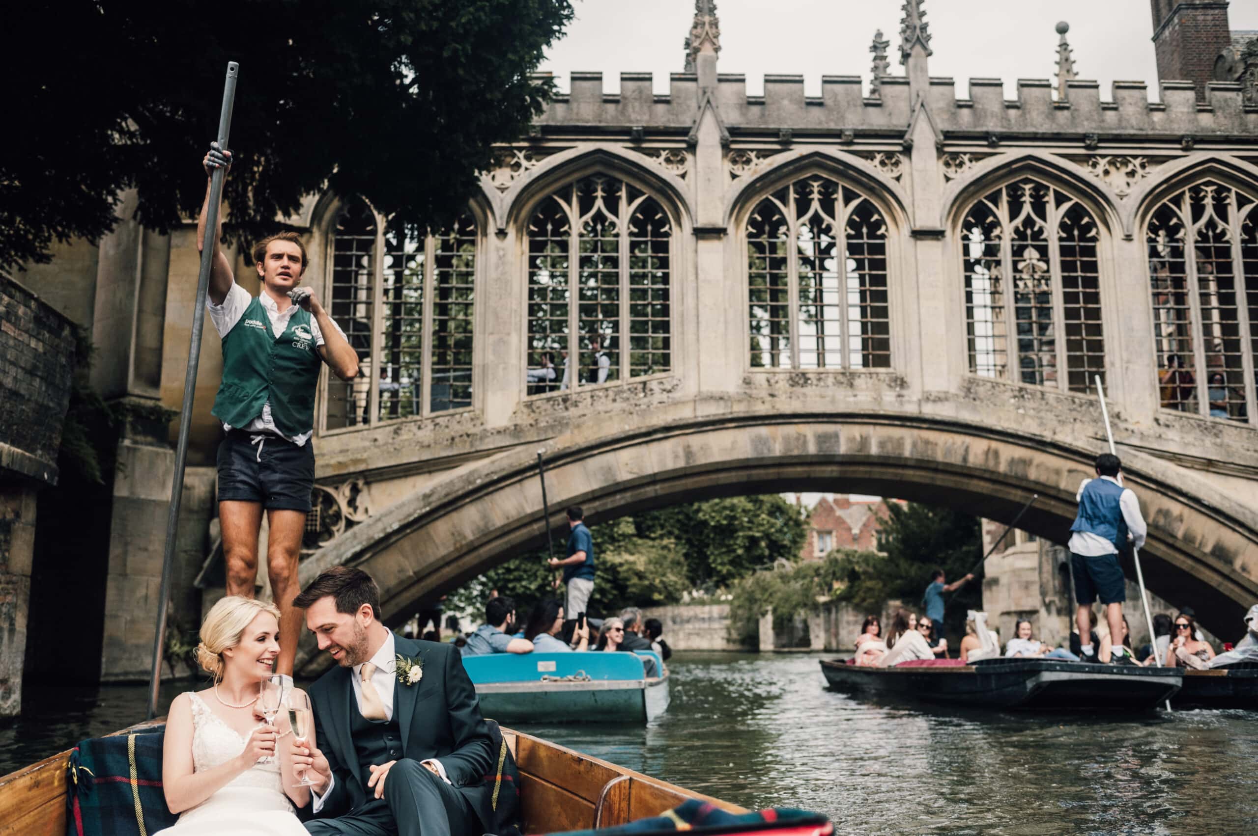 Bride and groom sharing a glass of champagne on board a punt along the river cam during their wedding in Cambridge.