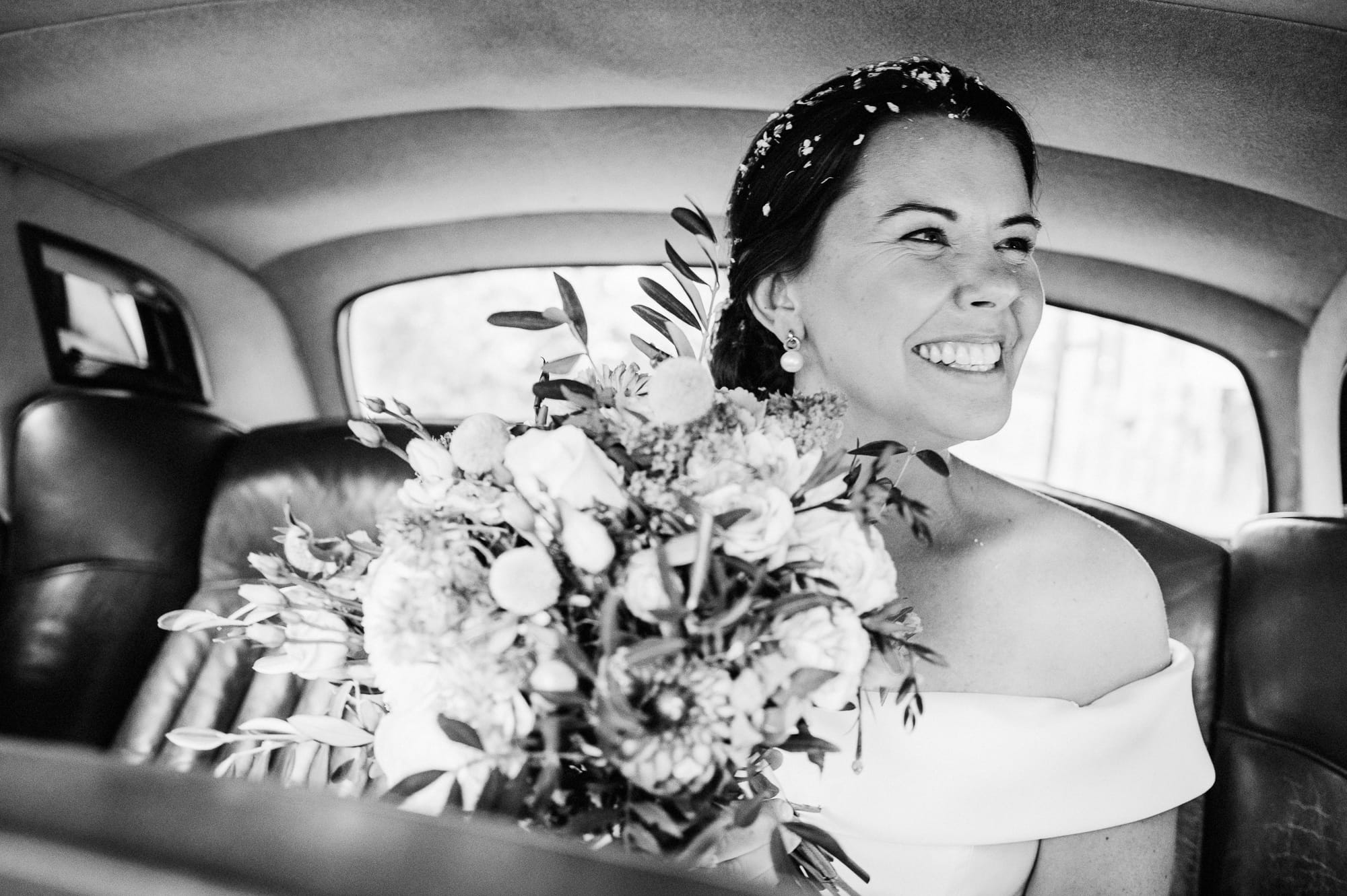 Bride smiles in her wedding car.