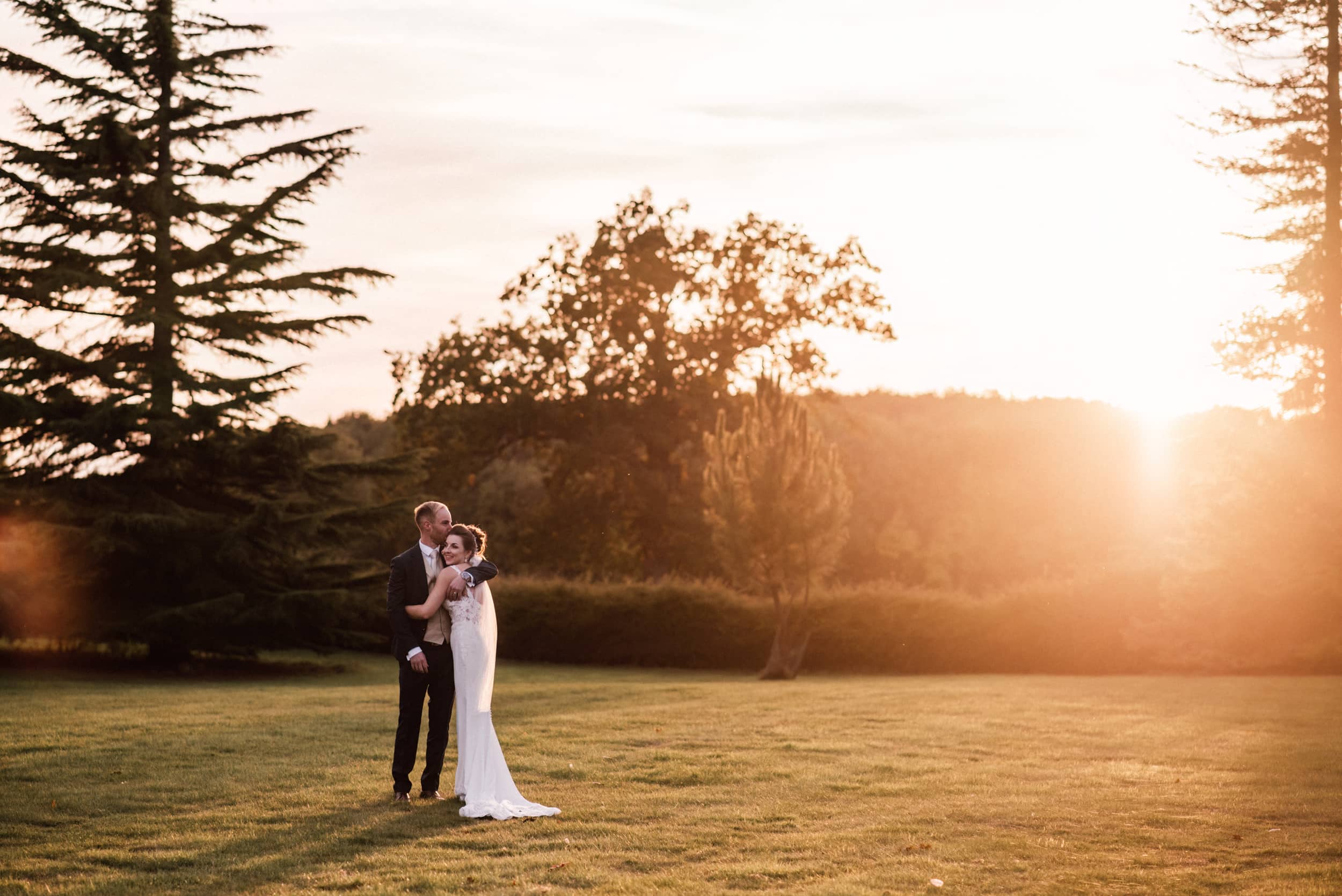A Newlywed couple embrace in the grounds of Holmewood Hall, Wedding Venue in Camridgeshire.